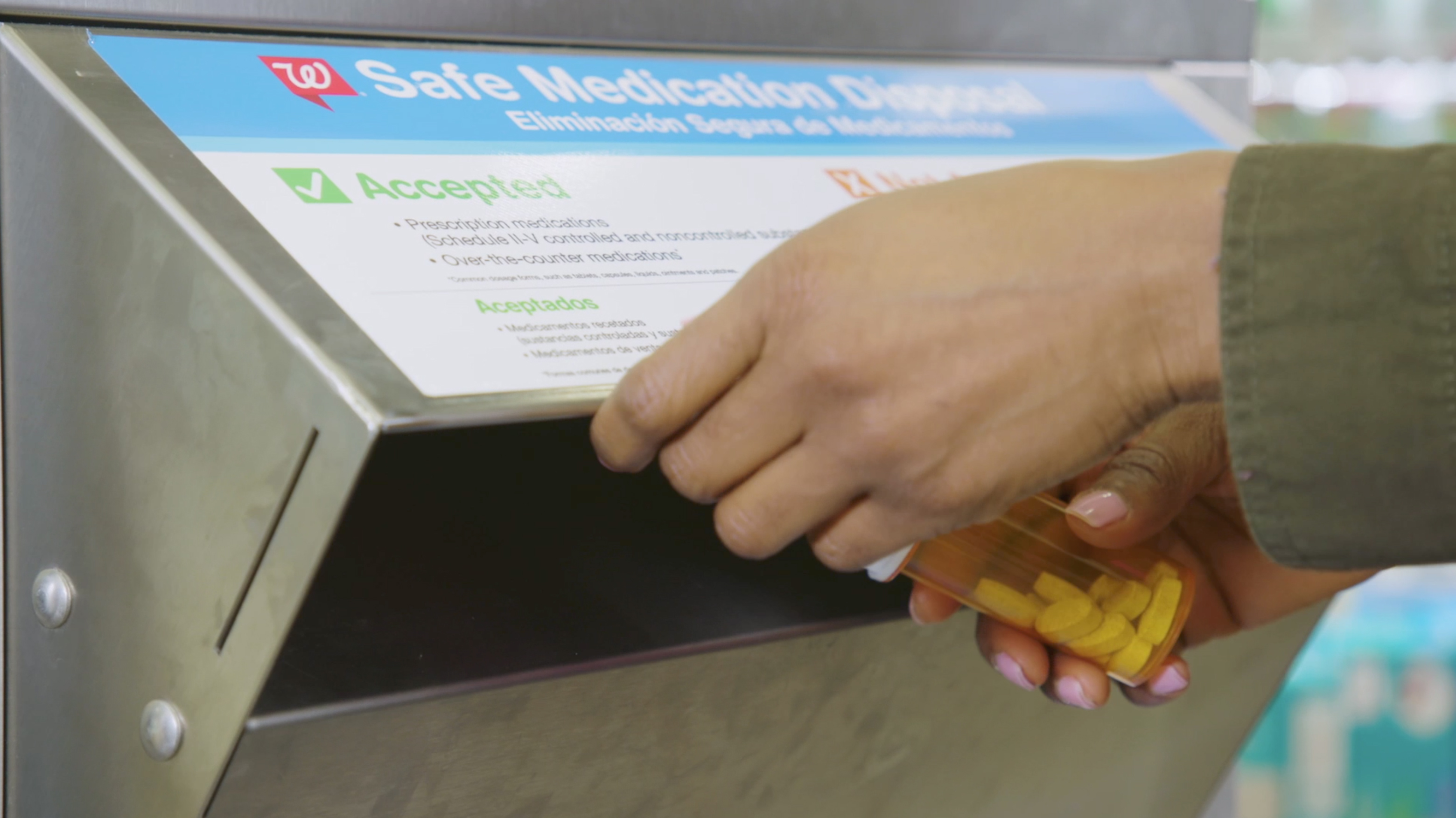 A person placing old medication into a safe medication disposal kiosk in Walgreens drugstore