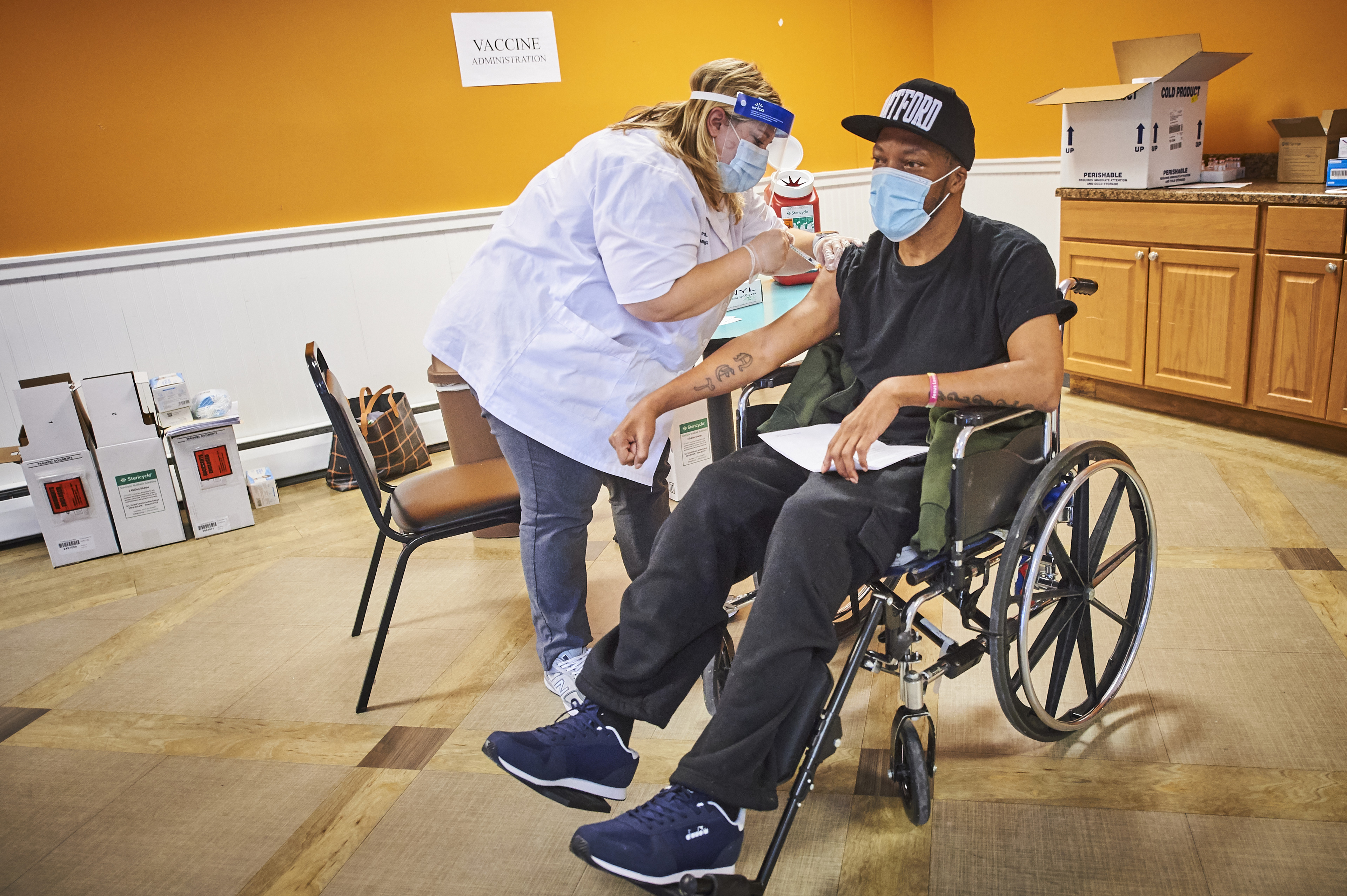 Patient in wheelchair getting the COVID-19 vaccine from Walgreens pharmacist