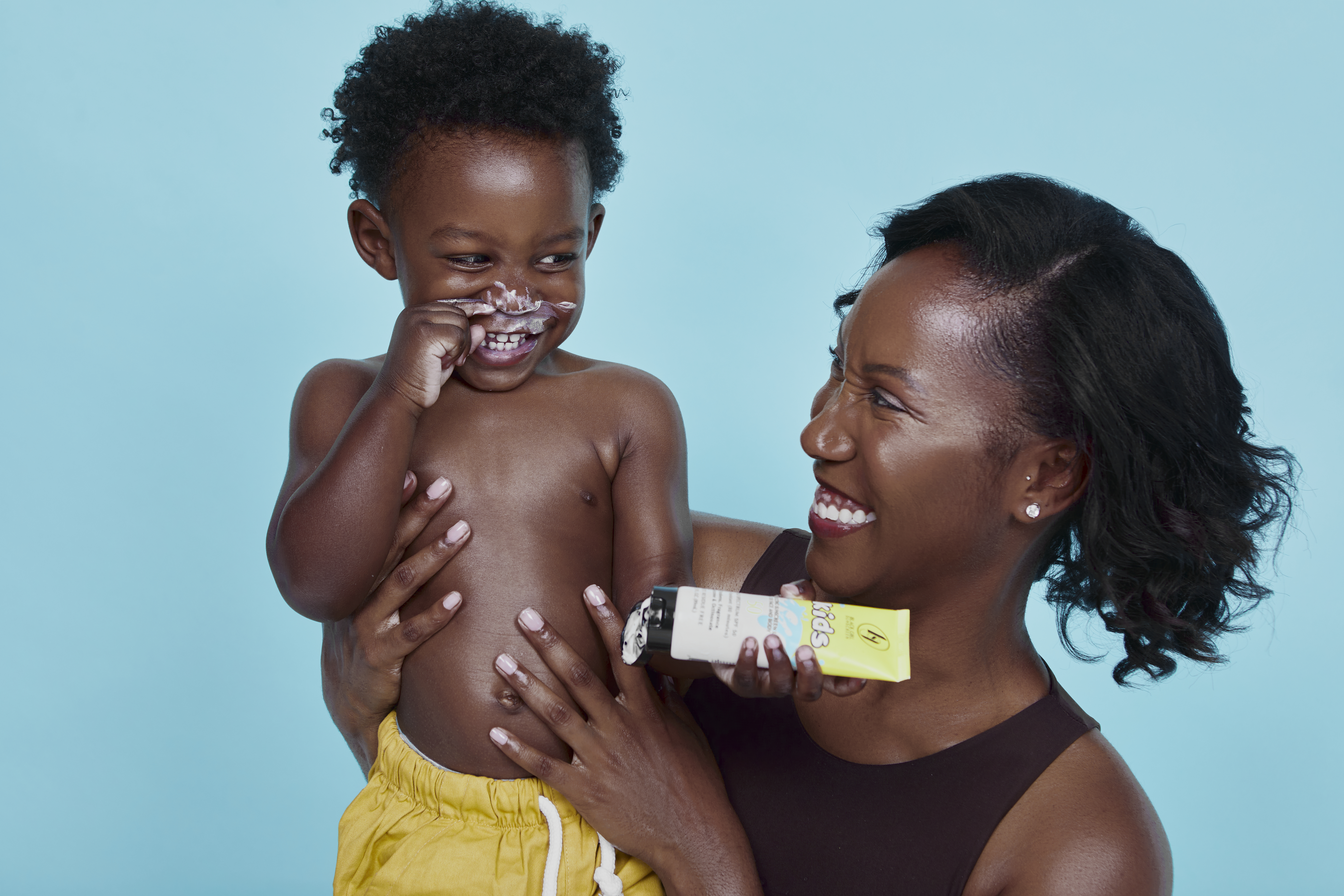 Black child and mother applying sunscreen