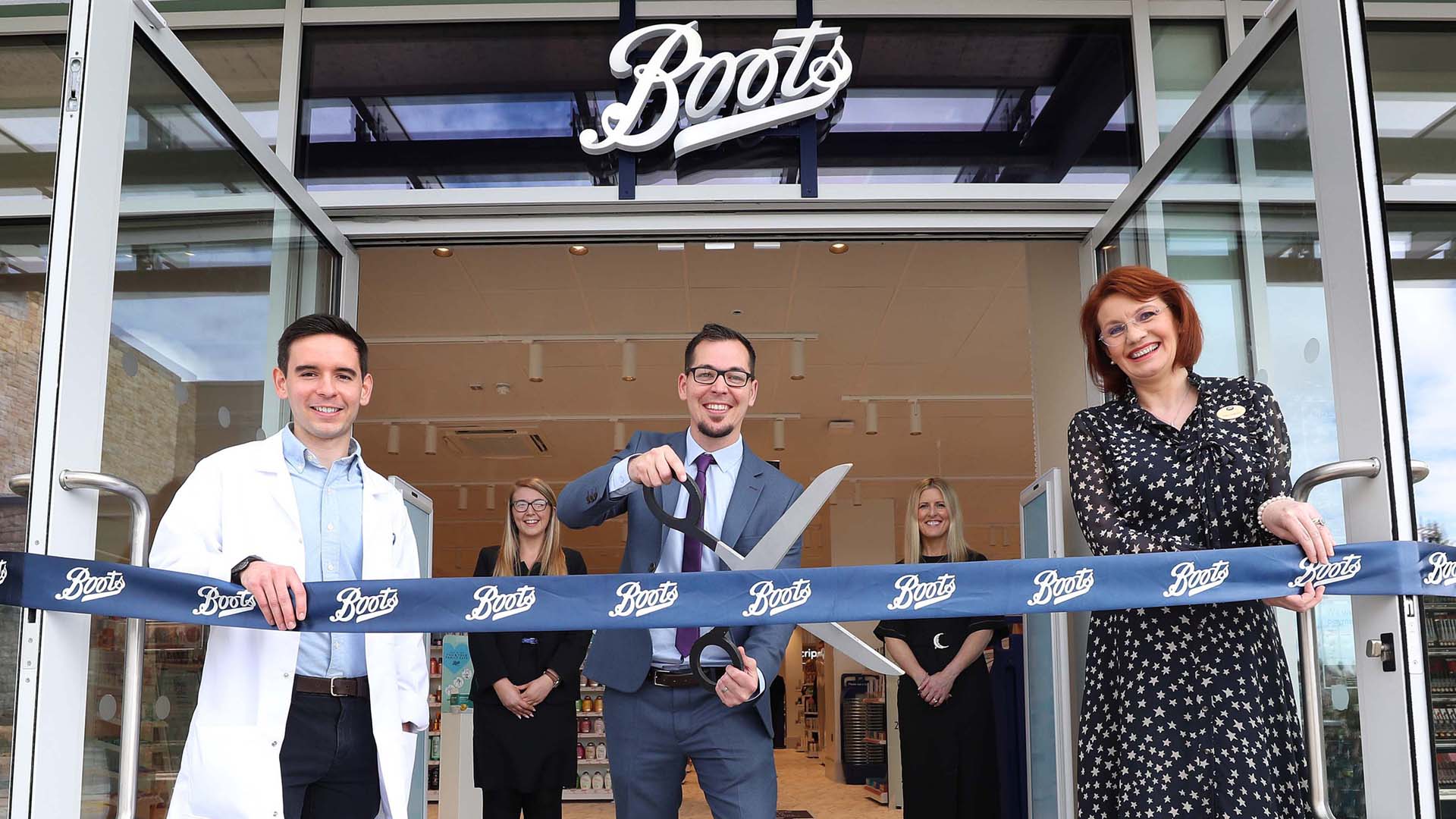 David Boyce, store manager, alongside store team, cutting the store opening tape with giant scissors outside of the Boots store in Knocknacarra, County Galway, Ireland