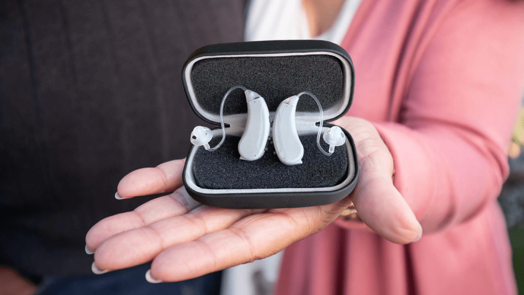 Hand holding a pair of hearing aids