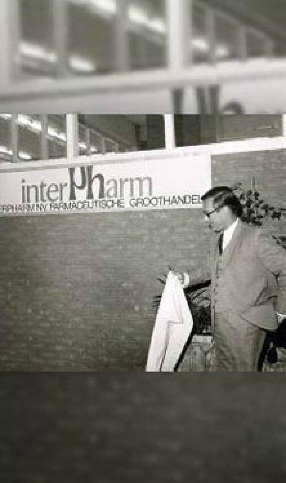 Man in a suit holding a white lab coat, pictured outside of Interpharm in The Netherlands