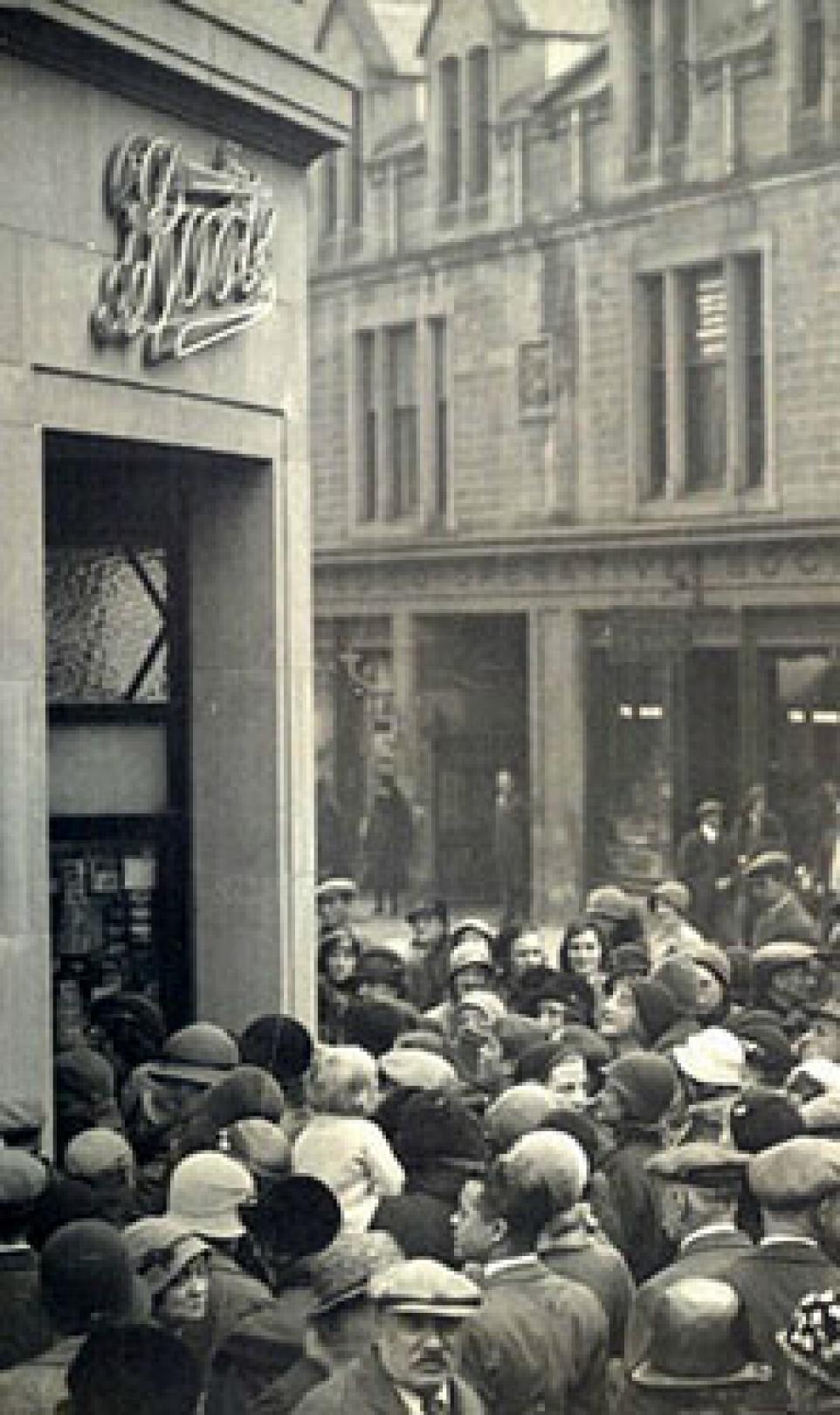 Black and white photo of a big crowd, gathering outside of the 1000th Boots store in the UK on its opening day