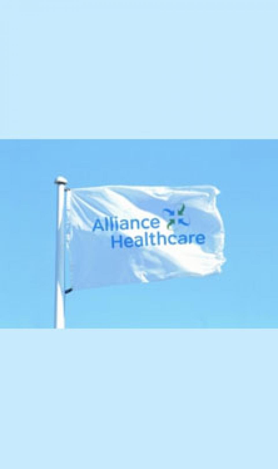 A white flag, blowing in the wind, featuring the blue and green Alliance Healthcare logo