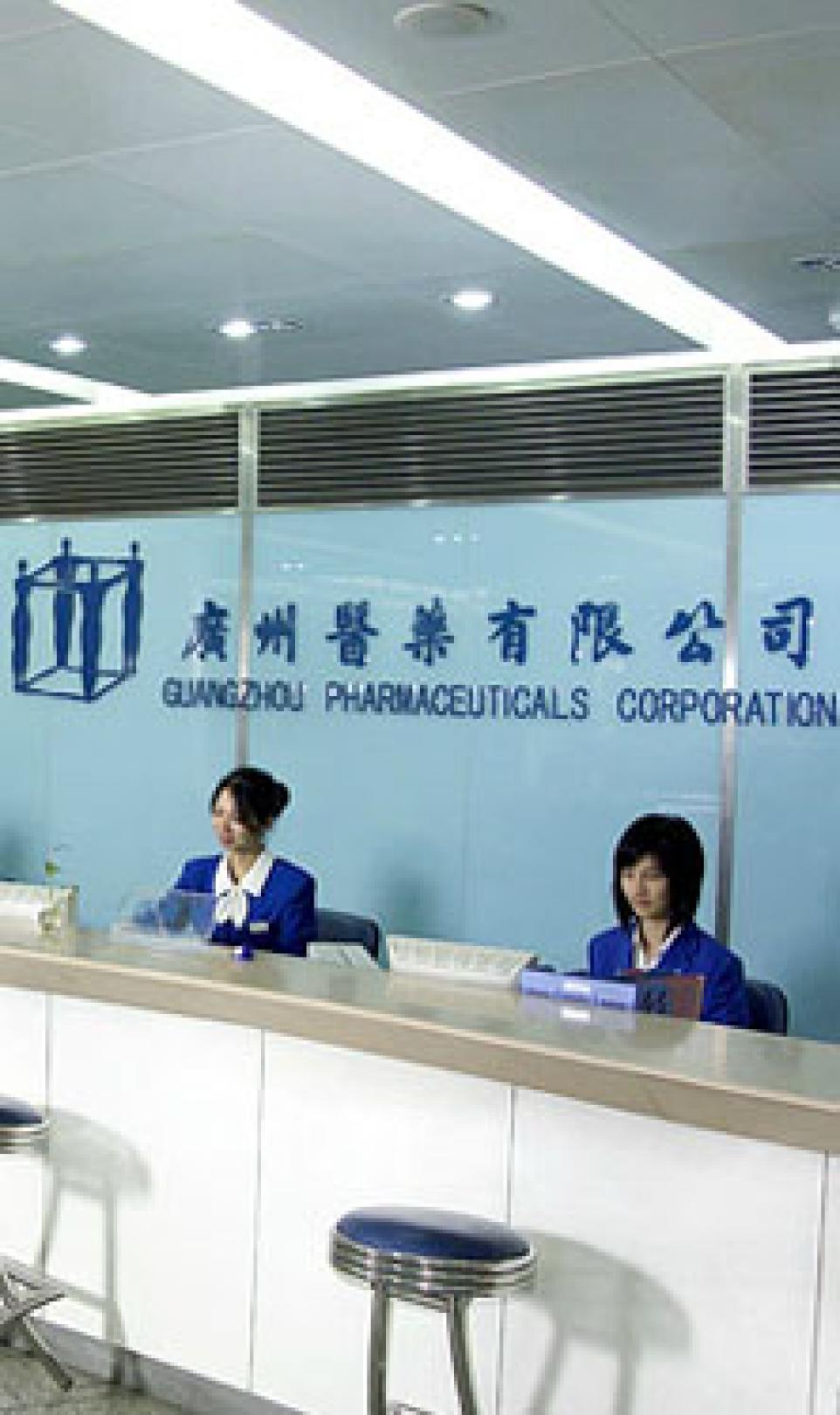 Two female receptionists in blue uniforms, pictured in the reception area of the Guangzhou Pharmaceuticals Corporation