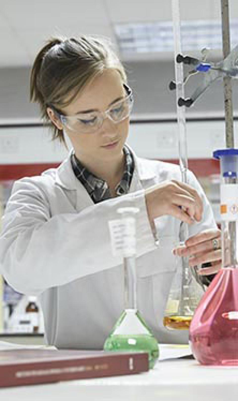 A female Walgreens technician in a white lab coat, pictured working in a laboratory