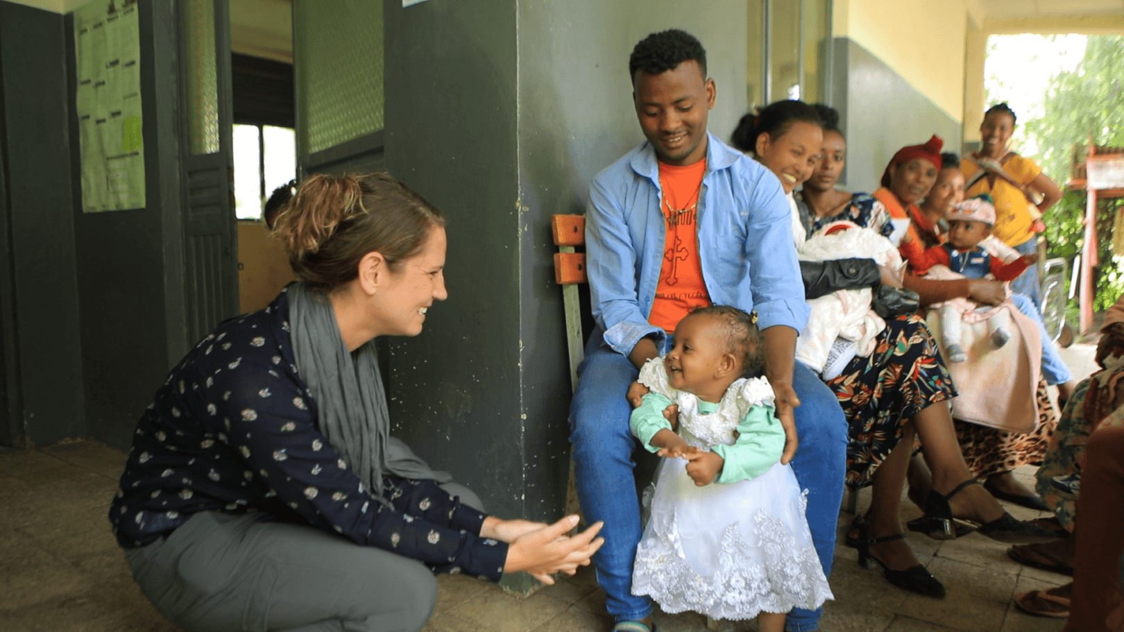 Walgreens team member Dorothy Loy (left) laughs with a father and daughter at a health clinic in Ethiopia.