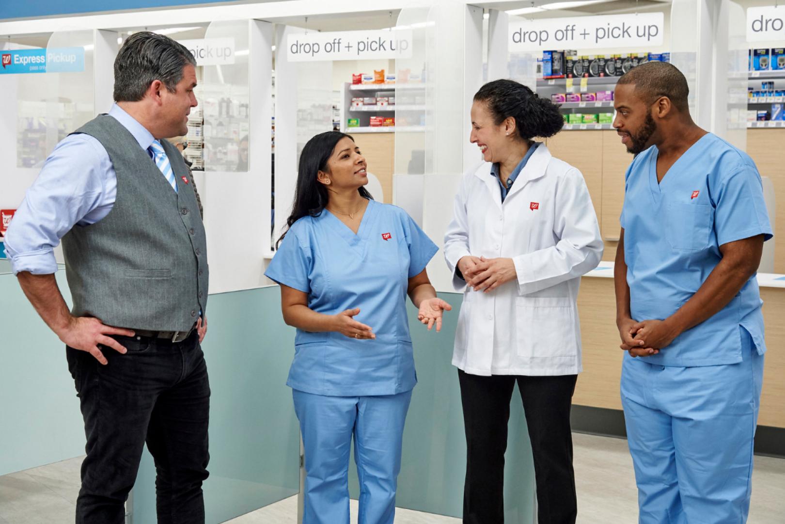 Four Walgreens colleagues talking together in a Walgreens drugstore