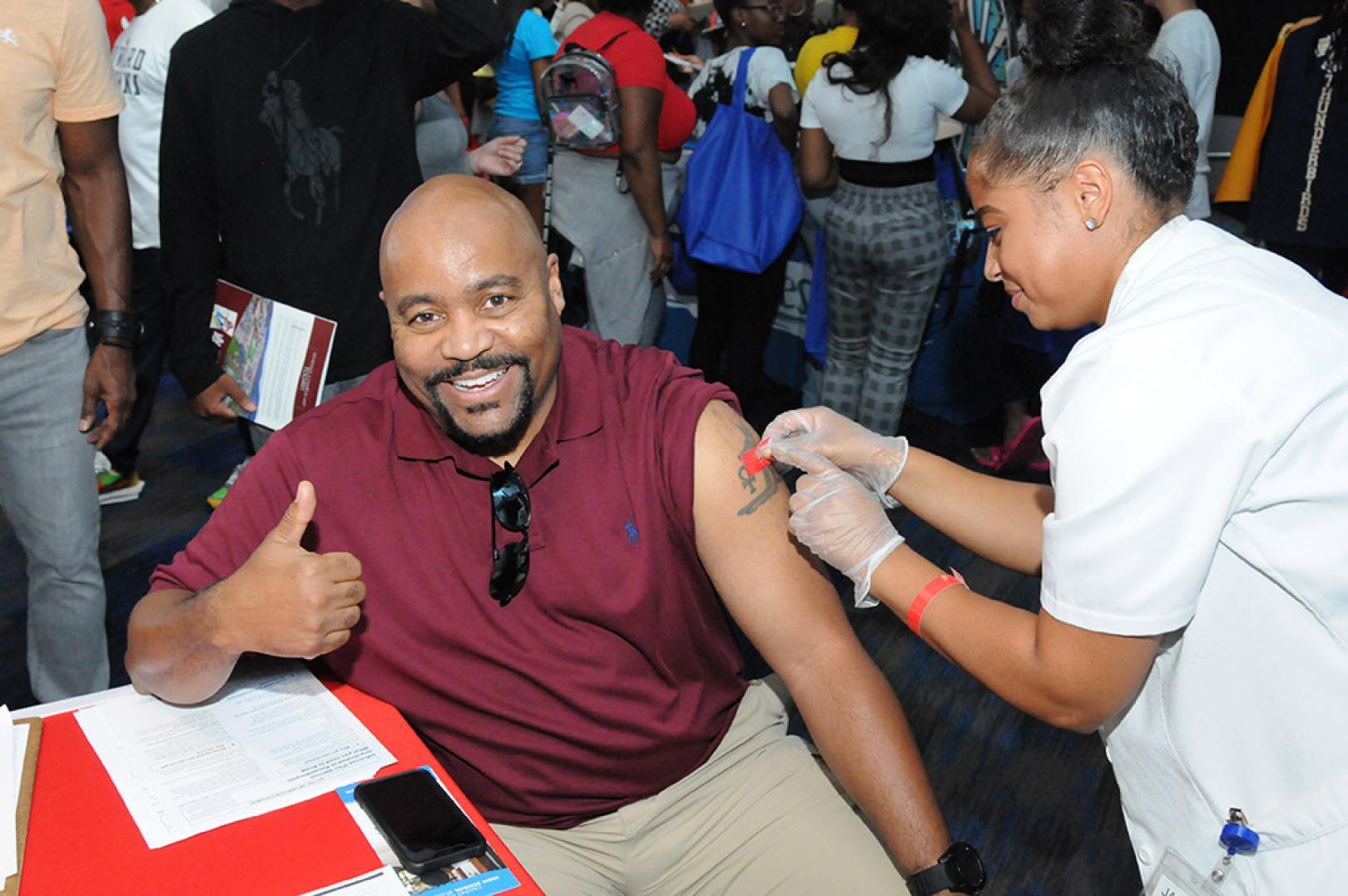 Man having plaster placed on arm by a Walgreens colleague after flu jab