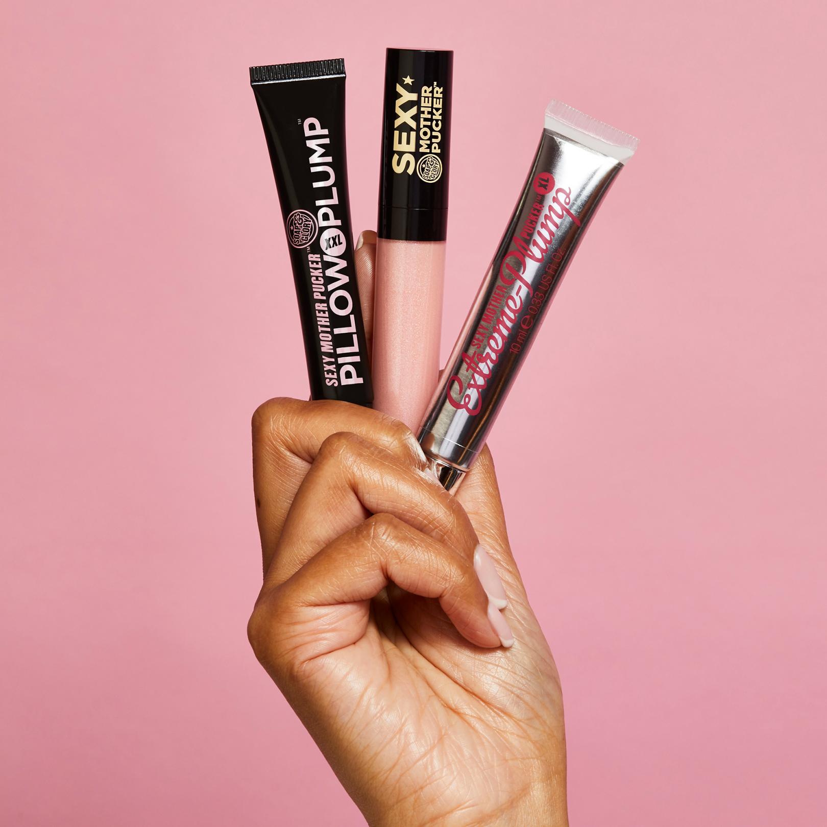 Hand holding three Soap and Glory lip glosses