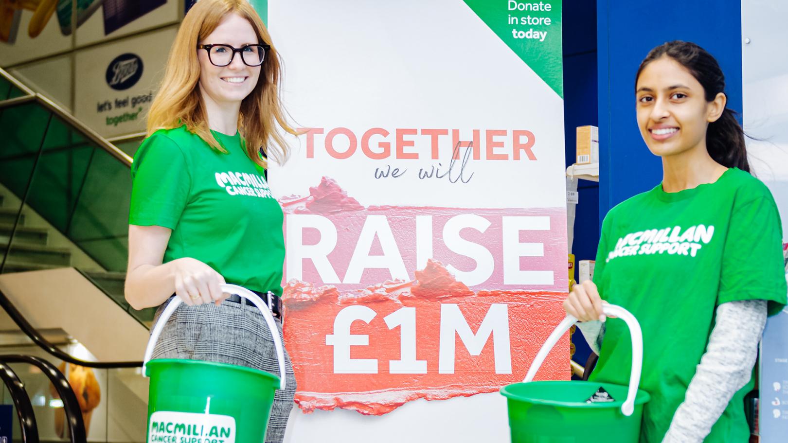 Two MacMillan volunteers holding donation buckets smiling at the camera