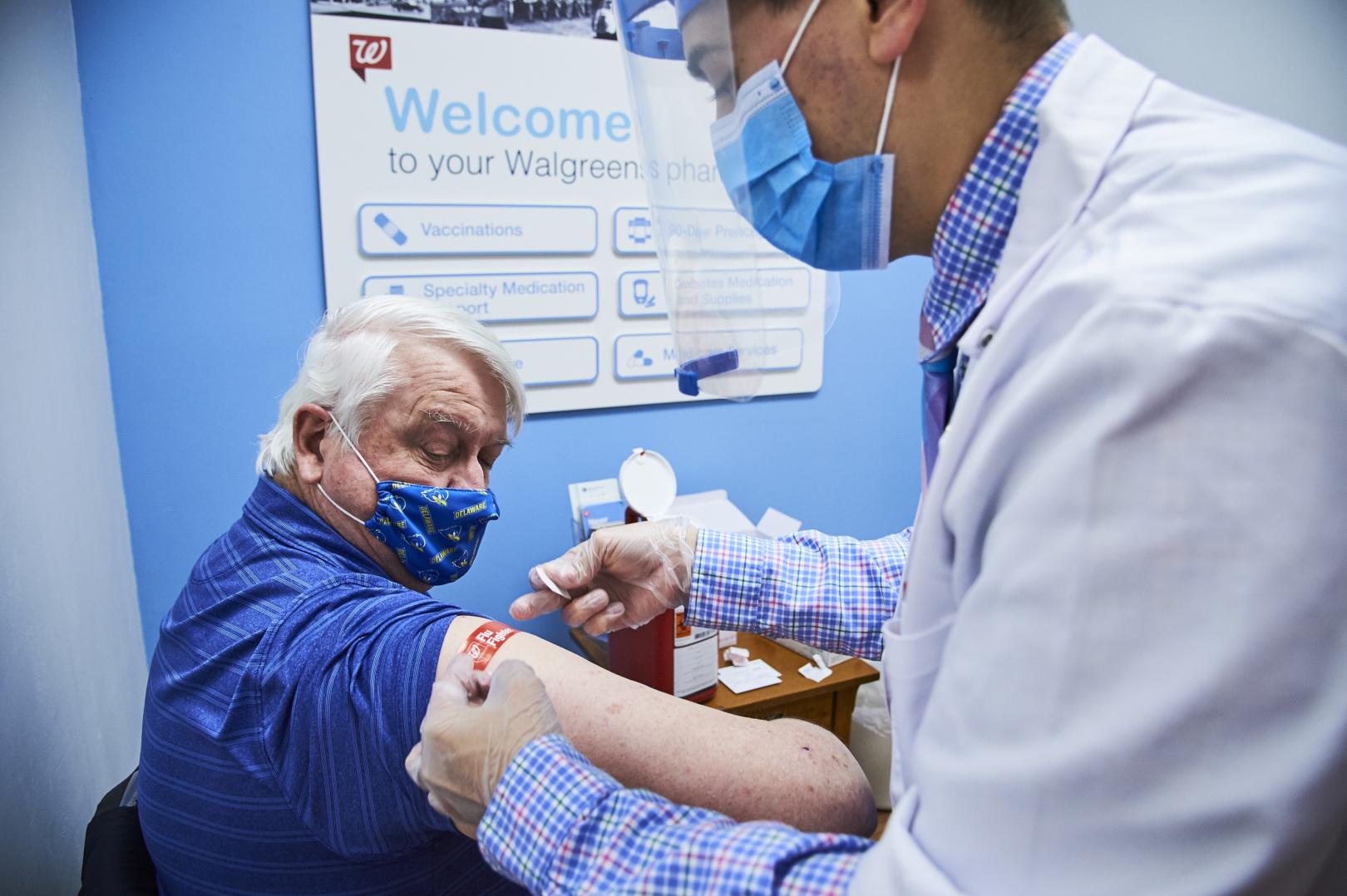 Male pharmacist administering vaccine to male patient
