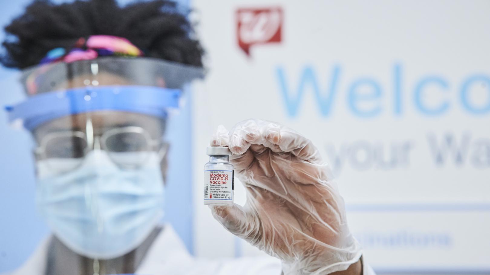 Walgreens team member holding a COVID-19 vaccine vial.