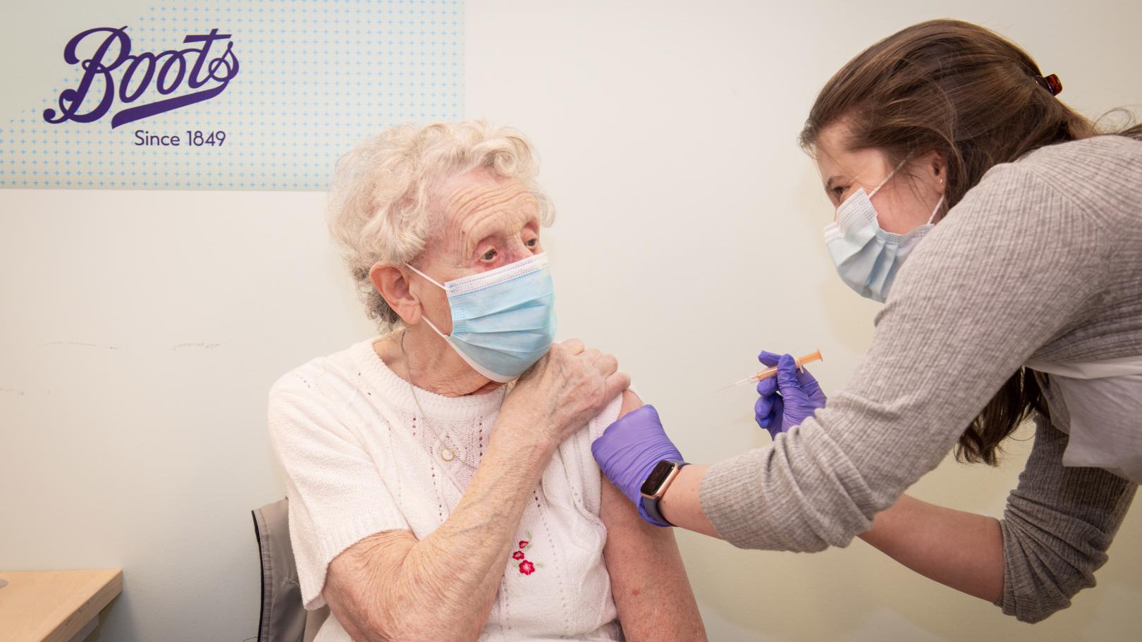 Brenda Clegg receiving COVID-19 vaccine from a team member at a Boots drugstore in Halifax, UK