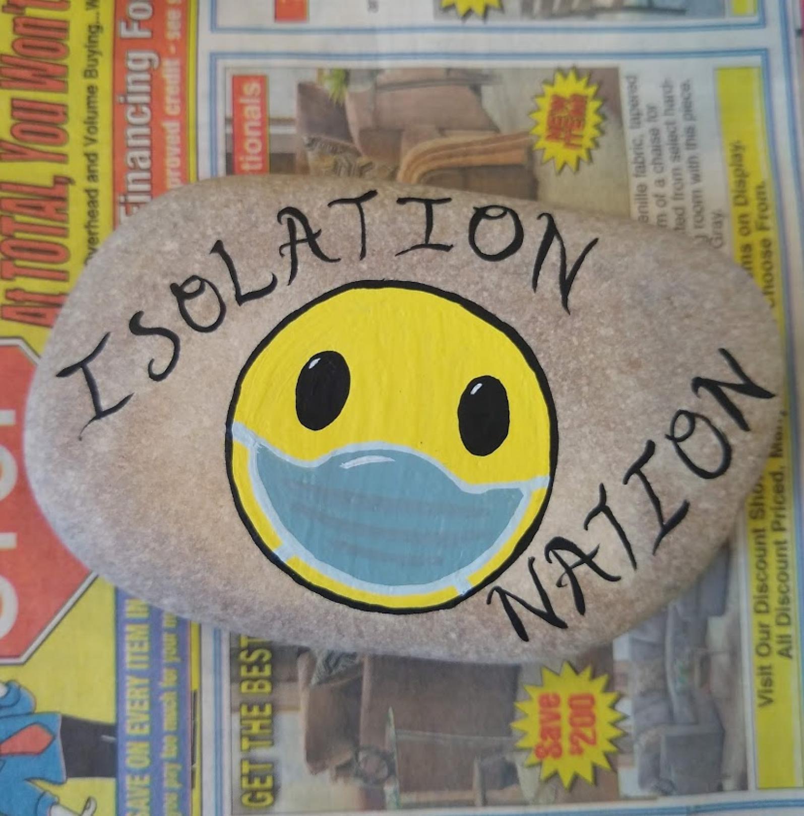 Painted rock saying "isolation nation"
