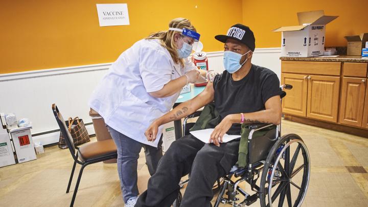 Patient in wheelchair getting the COVID-19 vaccine from Walgreens pharmacist