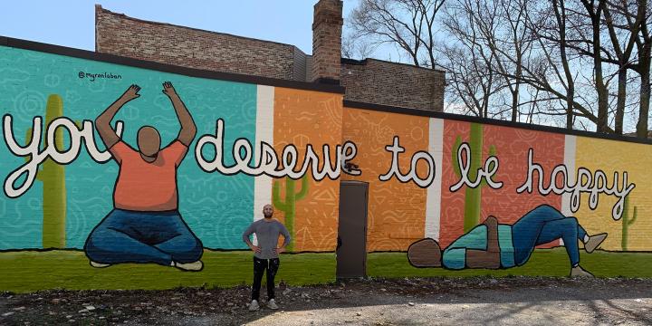 Myron standing next to one of his mural