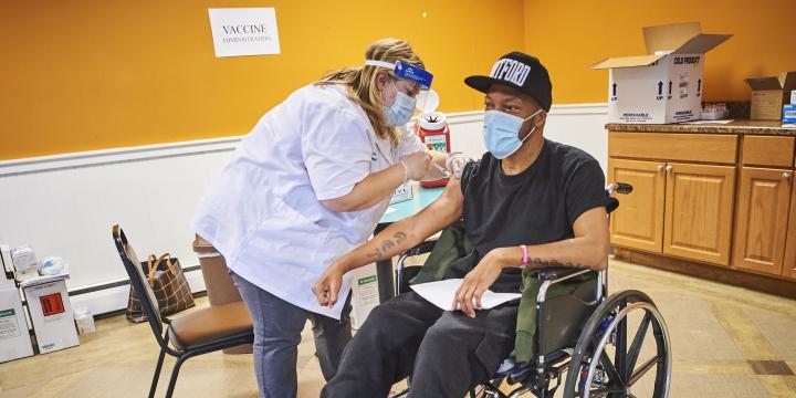 Patient in wheelchair getting the COVID-19 vaccine from Walgreens pharmacist