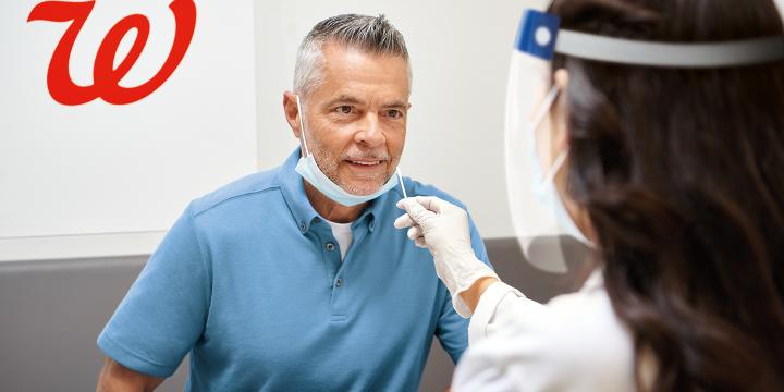 Man receiving a respiratory illness test by female Walgreens pharmacist