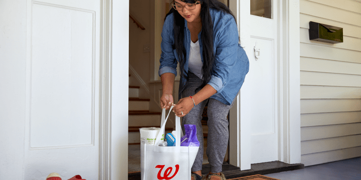Woman picking up Walgreens bag from porch